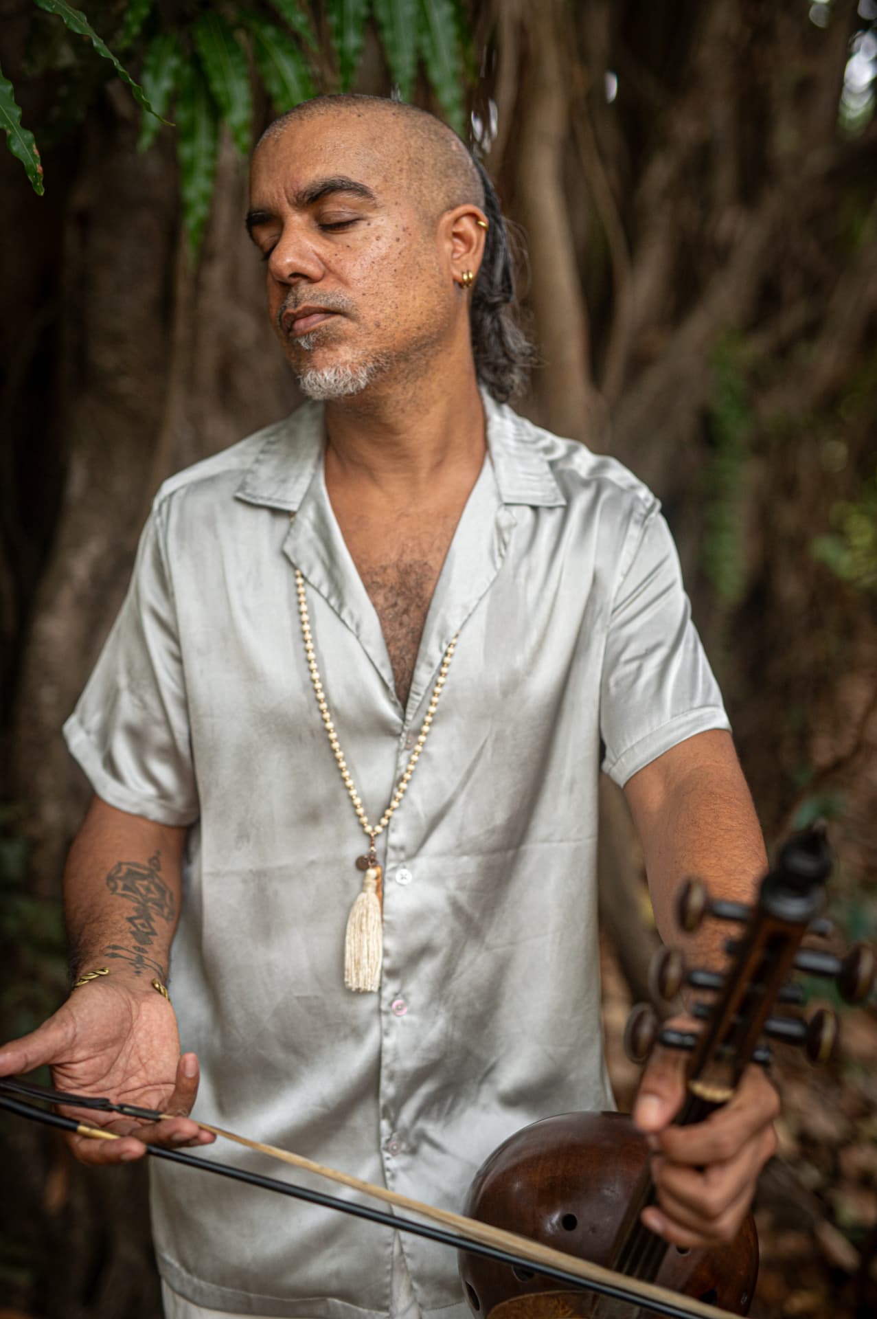 Roy Smila holding a kamancheh in the forest
